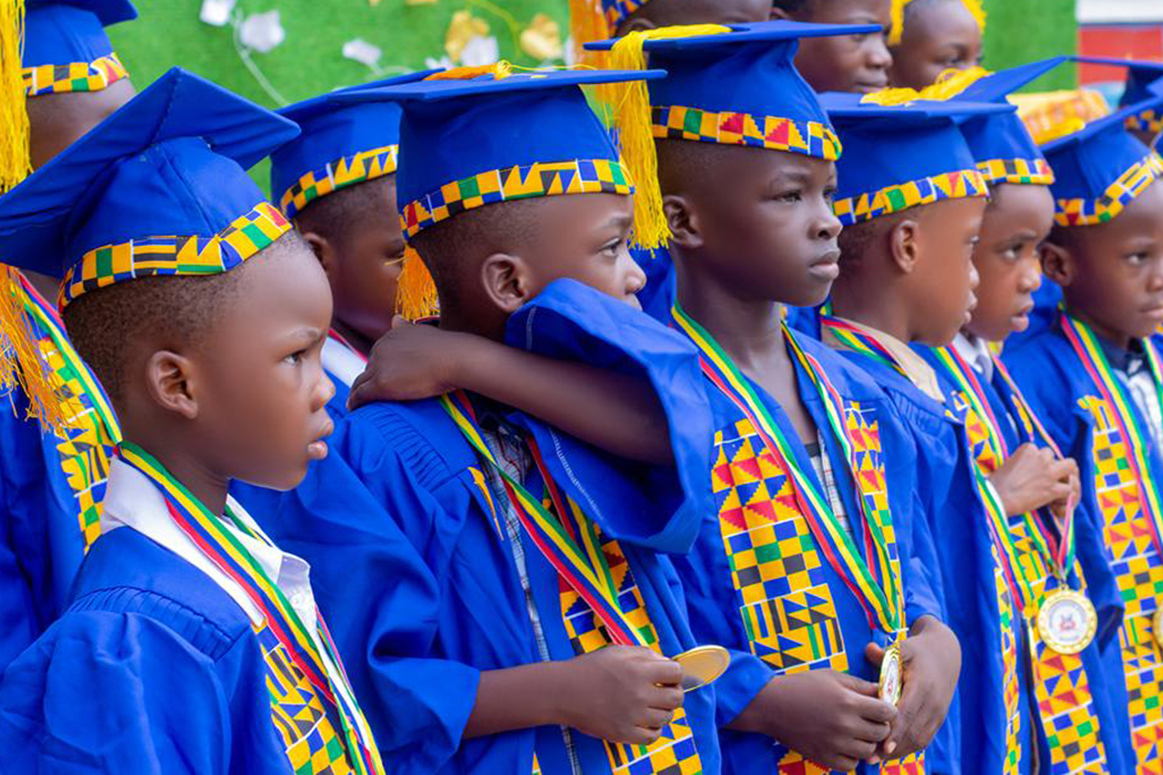 Students in graduation attire with colorful kente stoles